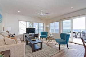 uma sala de estar com um sofá e cadeiras e uma televisão em Ocean Villas Beach Front em Carlsbad