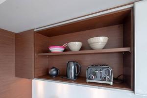 a shelf with bowls and a toaster and dishes on it at Clean 3rd Floor 1 BR Apt in Old Town China Town in Victoria