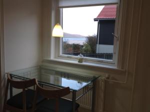 a glass table and two chairs in a room with a window at Appartment Glóm C in Tórshavn