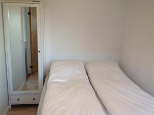Cama blanca en habitación con espejo en Appartment Glóm C, en Tórshavn