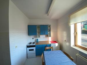 a kitchen with blue cabinets and a stove and a table at Chata - Penzión Oravice in Zákamenné