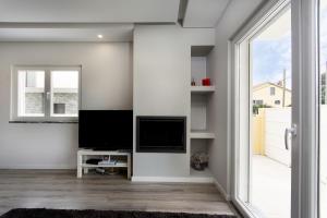 sala de estar con TV de pantalla plana junto a una ventana en A.V Holidays, en Fernao Ferro