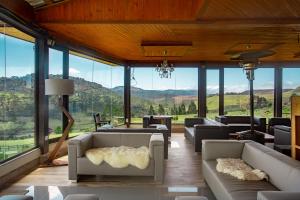 a living room with couches and tables and windows at Hotel Fazenda Rota dos Cânions in Bom Jardim da Serra
