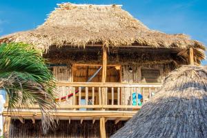 a hut with a straw roof and two palm trees at Hotel Del Rio in San Pedro
