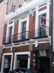 - un grand bâtiment en briques avec des balcons dans une rue dans l'établissement Hotel De Talavera, à Puebla
