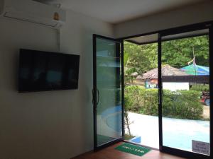 een kamer met een tv en een glazen schuifdeur bij Seahorse Lipe Hostel in Ko Lipe