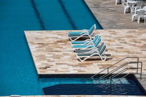 zwei Liegestühle neben einem Pool in der Unterkunft Flat térreo Palm Village Acqua Porto de Galinhas in Porto De Galinhas