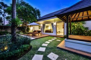 a garden with a patio and a house at The Yubi Boutique Villas Seminyak - CHSE Certified in Seminyak