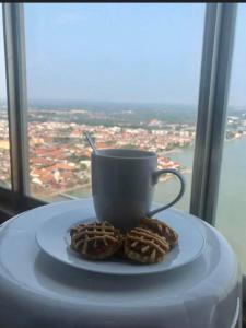 a cup and cookies on a plate in front of a window at Silverscape Seaview B25-13 in Malacca