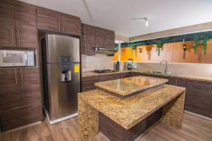 a kitchen with wooden cabinets and a stainless steel refrigerator at The Traveler Hostel in Otavalo