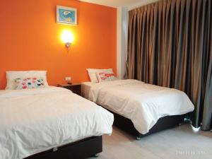 two beds in a room with orange walls at Dozy House in Chiang Mai