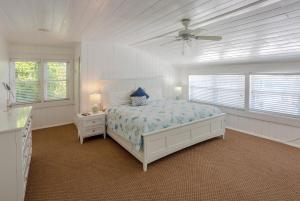 a white bedroom with a bed and a ceiling fan at Twins Inn & Apartments in St Pete Beach