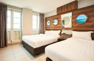 a hotel room with two beds and two mirrors at ibis budget Singapore Selegie in Singapore +62 photos