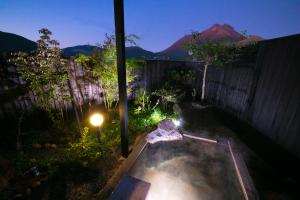 a backyard with a hot tub in the yard at night at Yufuin Bath Satoyamasafu in Yufu