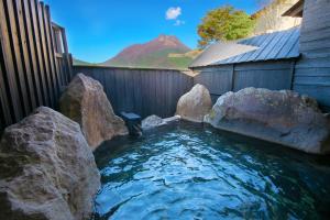 a pool of water with rocks in a backyard at Yufuin Bath Satoyamasafu in Yufu