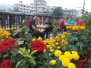 eine Gruppe von Menschen, die um einen Garten mit Blumen herum sitzen in der Unterkunft Harvest Moon Guest House in Pokhara