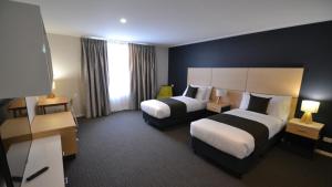 古尔本The Astor Suites的一间有两张床和两盏灯的酒店房间