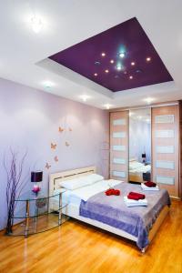 - une chambre avec un grand lit et un plafond violet dans l'établissement Apartments Kiselyova, à Minsk