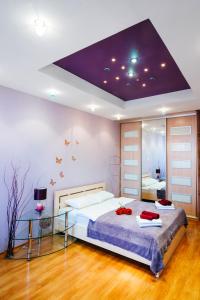 a bedroom with a large bed with a purple ceiling at Apartments Kiselyova in Minsk