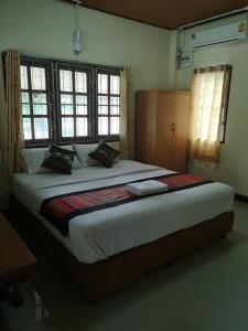 ein großes Bett in einem Zimmer mit Fenstern und einem Bett sidx sidx sidx in der Unterkunft Mitaree 2 in Mae Sariang