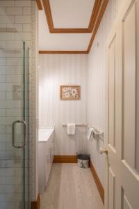 baño con ducha, lavabo y puerta en Settlers Cottage Motel, en Arrowtown