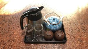 a tea kettle and glasses on a tray on a table at OSHI-KIKUYABO Mt-Fuji Historic Inn in Fujiyoshida