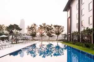a swimming pool in front of a building at Ibis Bangkok Riverside in Bangkok