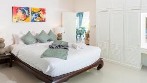 una camera bianca con un grande letto bianco con cuscini di 3 BR Villa Baan Khwam Rak, seconds to beach a Lamai Beach Altre 27 foto