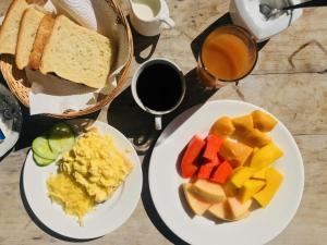 a table with two plates of breakfast foods and a cup of coffee at Villa Des Flots in La Réunion