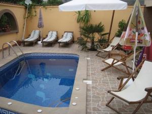 ein Swimmingpool mit Stühlen und einem Sonnenschirm sowie einem Tisch und Stühlen in der Unterkunft Family Hotel Hit in Kiten