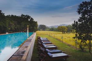 
a row of picnic tables sitting on top of a lush green field at Sigiriana Resort by Thilanka in Dambulla
