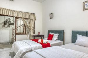 a bedroom with two beds and a window at RedDoorz Syariah @ Raya Tajem Maguwo in Kalasan