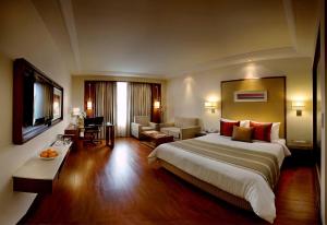 Habitación de hotel con cama grande y sala de estar. en Park Inn Gurgaon, en Gurgaon