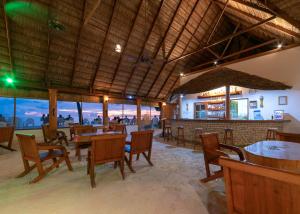 a restaurant with tables and chairs and a bar at Fihalhohi Maldives in South Male Atoll