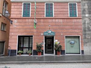 a pink brick building with green shutters and a door at Albergo Posta in Genoa