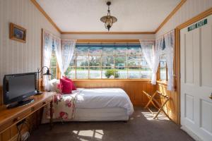 a bedroom with a bed and a television and a window at Settlers Cottage Motel in Arrowtown