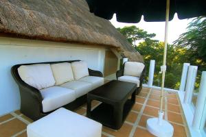 un sofá y una silla en un patio con sombrilla en Tropicana Ocean Villas, en Boracay
