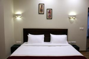 a bedroom with a bed with white sheets and two lights at Hotel Dasaprakash in Agra