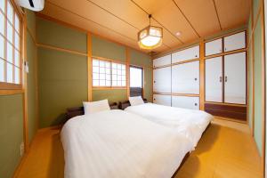 a bedroom with a large white bed and windows at Oyado E-TIME Tamade Annex in Osaka