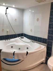 a white bath tub in a bathroom with a toilet at Acfes-Seiyo Hotel in Vladivostok