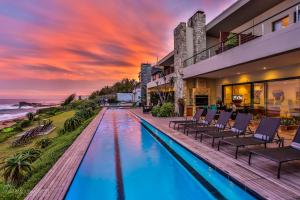 a resort pool with chairs and a sunset at Canelands Beach Club in Ballito