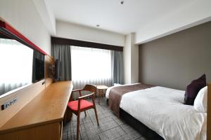 una camera d'albergo con un letto, una scrivania e una TV di Hotel Granvia Hiroshima a Hiroshima