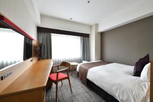 a hotel room with a bed and a desk and a tv at Hotel Granvia Hiroshima in Hiroshima