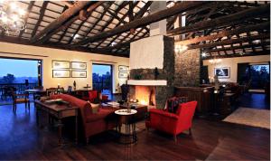 a living room with red chairs and a fireplace at Samode Safari Lodge in Parāsi