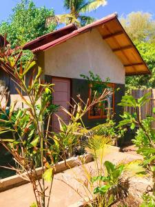 a small house with a door in a garden at Santai Bungalow in Gili Trawangan