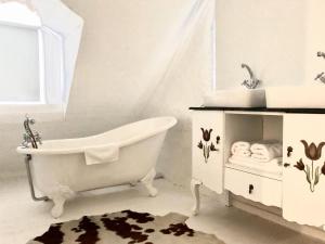 a white bathroom with a tub and a sink at Drewry Lane in Howick