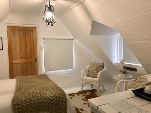 a bedroom with a bed and a chair and a window at Drewry Lane in Howick