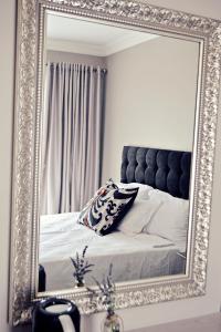 una camera da letto con specchio e letto con testiera di Bokmakierie Gastehuis Emalahleni Pty Ltd a Witbank