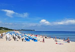 una folla di persone su una spiaggia con sedie blu e persone di Ferienwohnungen im Ostseebad Goehr a Göhren