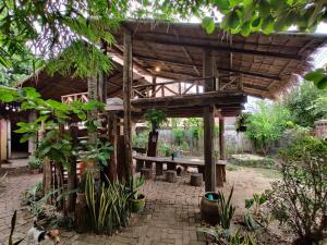 a wooden pergola with a bench in a garden at Bike&Bed in Thakhek